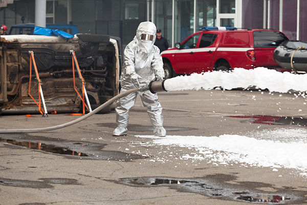 Fully hazard-suited firefighter cleaning up a toxic substance spill