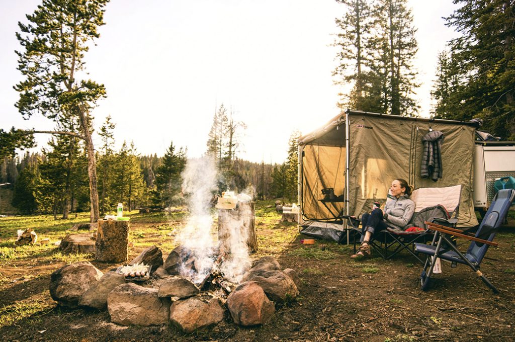 Woman in a camping chair near a campfire